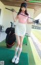 A woman in a pink shirt and white skirt holding a golf club.