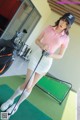 A woman in a pink shirt and white skirt holding a golf club.