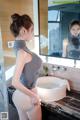 A woman standing in front of a bathroom sink.