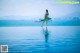 A woman in a blue bikini holding a surfboard in the water.