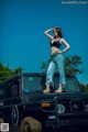 A woman standing on top of a black jeep.