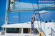 A woman standing on the deck of a sailboat in the ocean.