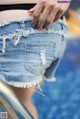 A woman in a black top and blue denim shorts.