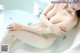 A woman sitting in a bathtub with a tattoo on her arm.