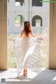 A woman in a white dress is standing in an abandoned building.