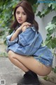 A woman in a denim jacket and black boots posing for a picture.