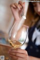 A woman holding a spoon over a glass of white wine.