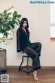 A woman sitting on a stool in a room.