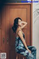 A woman sitting on a stool in front of a door.