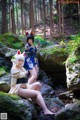 A couple of women sitting on top of a rock in the woods.