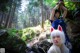 A woman in a blue and white kimono standing in the woods.