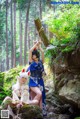 A couple of women sitting on top of a rock in the woods.