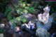 A couple of women sitting on top of a rock next to a stream.