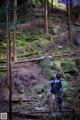 A woman in a blue kimono standing in the woods.