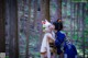 A couple of women in kimonos kissing in the woods.