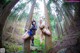 A couple of women sitting on top of a tree in a forest.