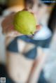 A woman holding a green pear in her hand.