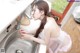 A woman in a pink lingerie is washing her hands in the sink.