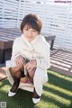 A woman in a white coat and black stockings sitting on a bench.