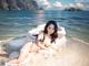 A woman laying on top of a white pillow on a beach.