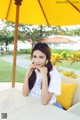 A woman sitting at a table under an umbrella.