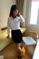 A woman in a white shirt and black skirt posing for a picture.