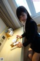 A woman sitting at a table with cups and saucers.