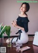 A woman sitting on a table next to a plant.