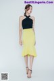 A woman in a black top and yellow skirt.