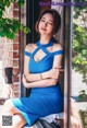 A woman in a blue dress sitting on a window sill.