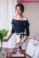 A woman standing next to a table holding a white bag.