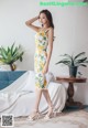 a woman standing in front of a couch wearing a yellow dress