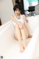 A woman sitting in a bathtub with her legs crossed.