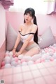 A woman sitting on top of a bed covered in pink and white balls.